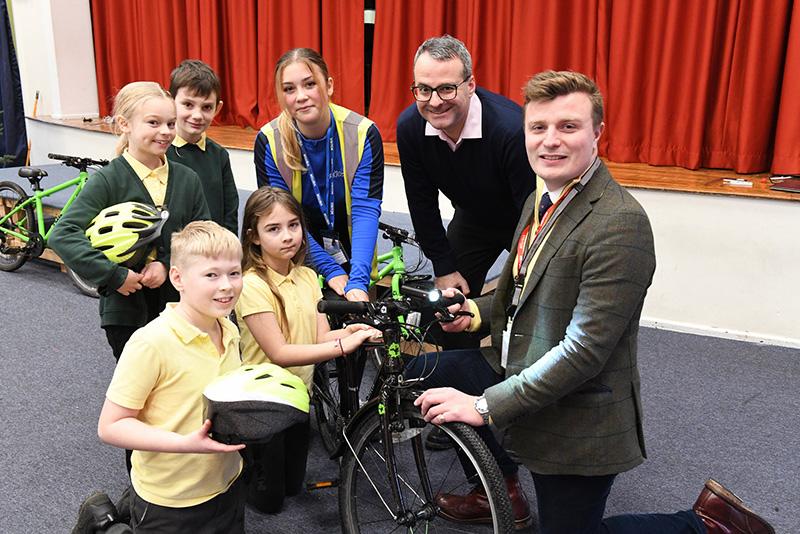 Councillor Mark Ieronimo (second right) and Deputy Police & Crime Commissioner, Leo Hammond, (right) present children from Priory Primary School with their free bike lights