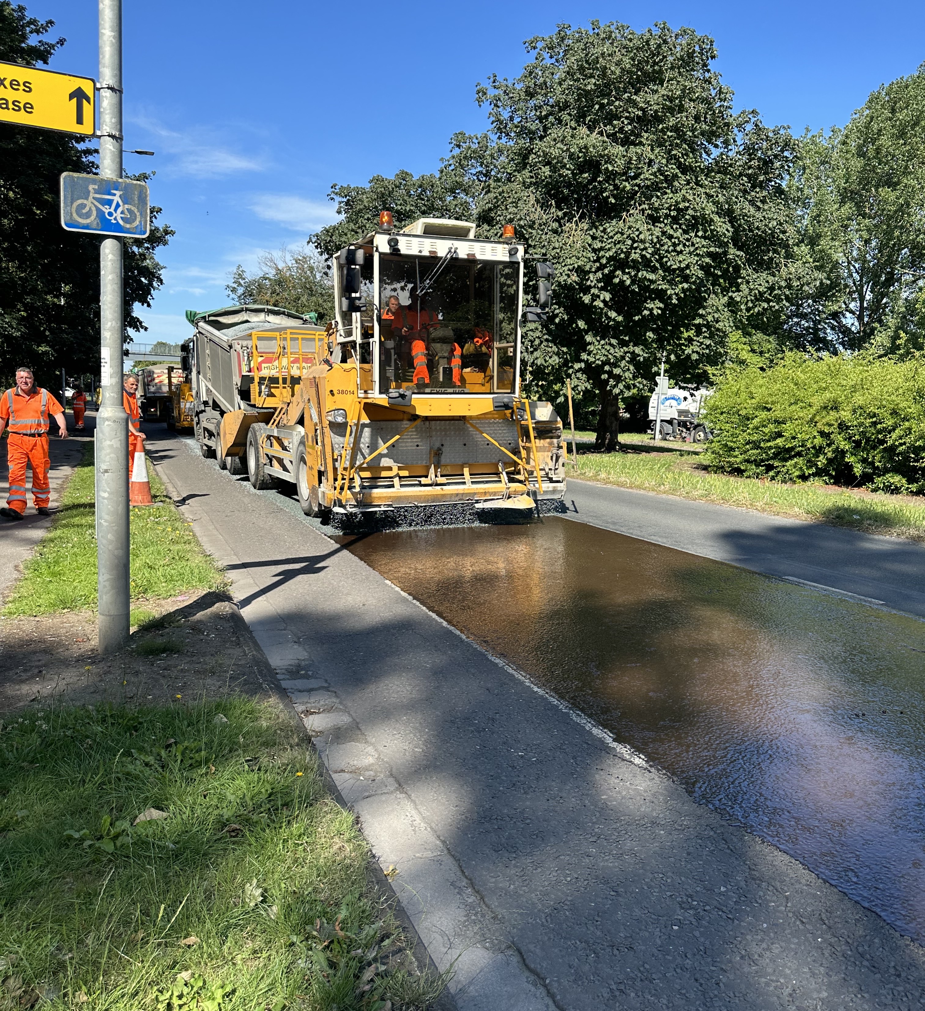 Council staff and machinery undertaking surface dressing work on a road