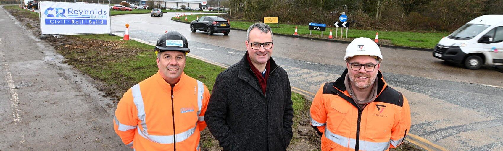 three men stood in front of a roundabout